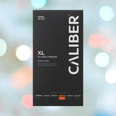 A black box of Caliber XL - Extra Large Condoms (60mm Wide) displays "Made to Fit", featuring softly blurred pastel bokeh lights in the background.